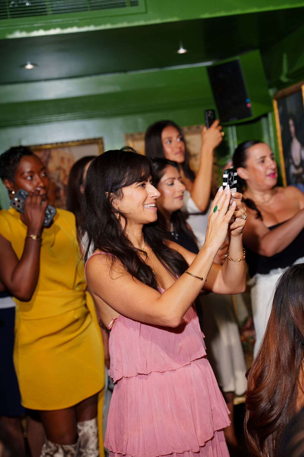 A woman in a pink dress capturing a moment among fellow guests