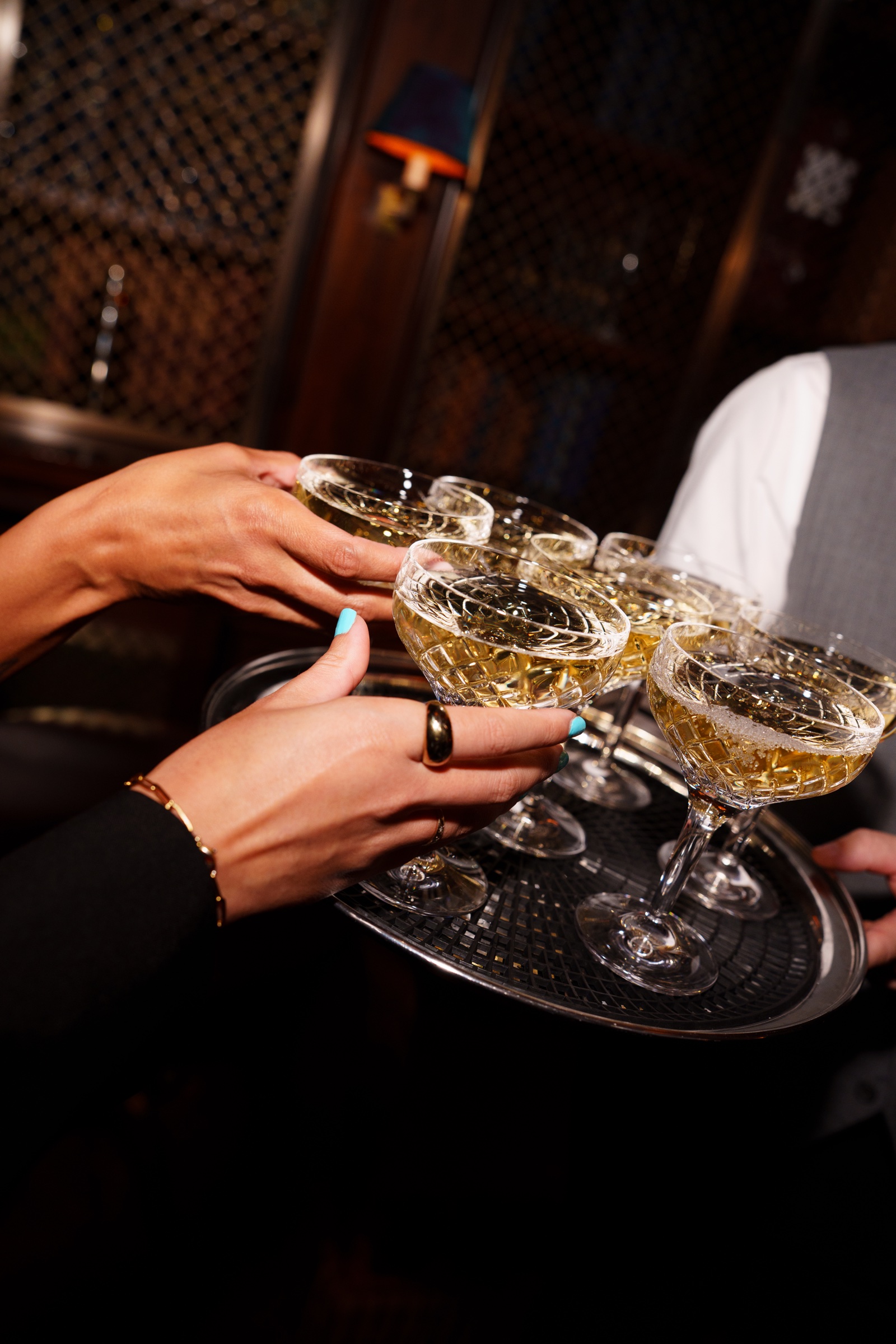 Guests taking cut-glass cocktails from a silver serving tray