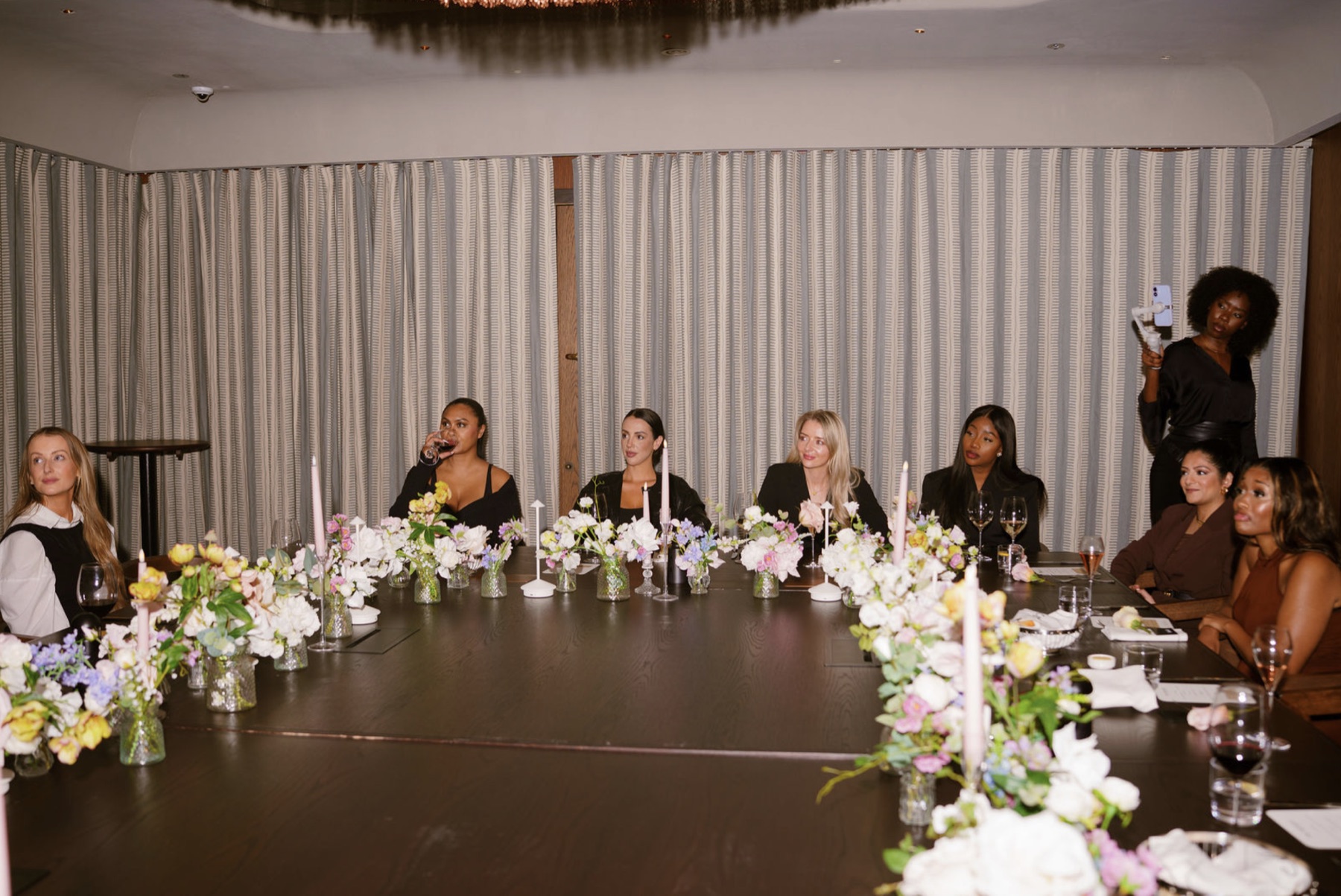 Women gathered around an elegantly dressed dinner table at a theCOLLECTIVE experience
