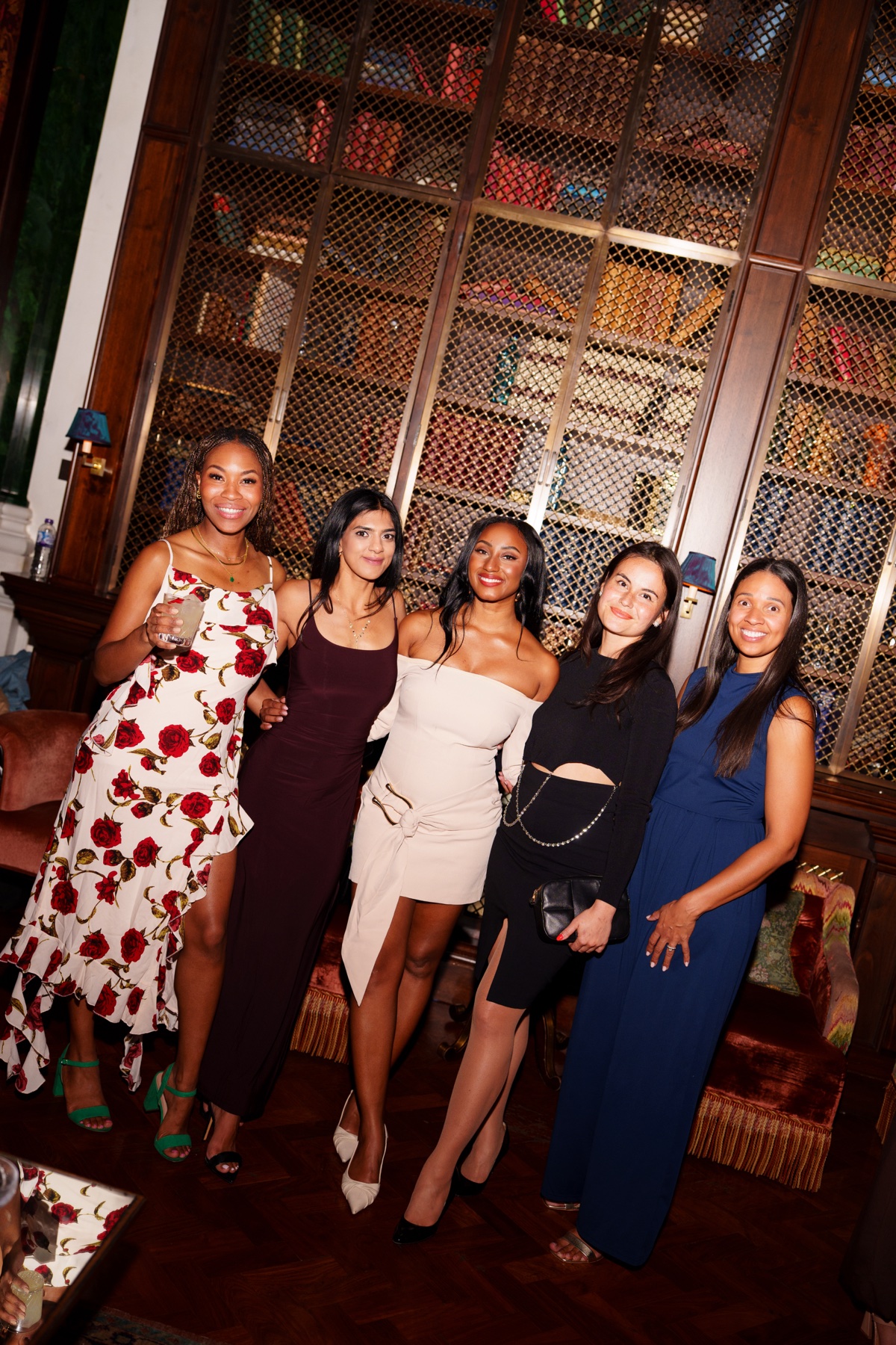 Five women posing together in front of tall library shelves