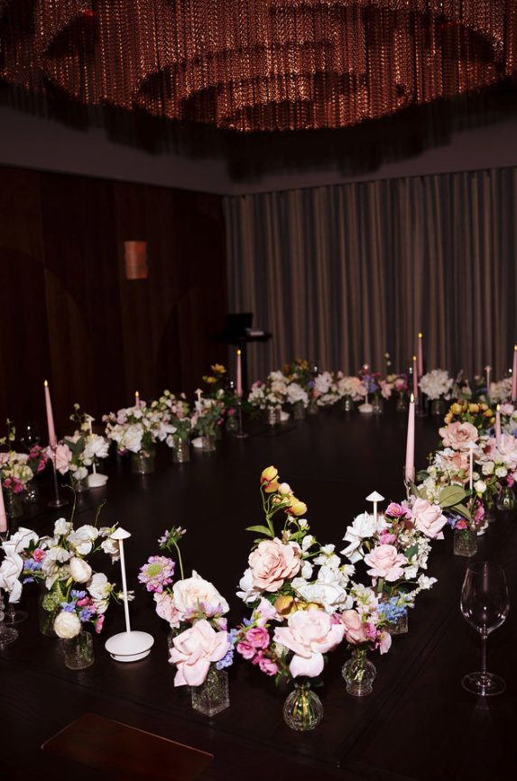 A candlelit dinner table arranged with flowers for a theCOLLECTIVE gathering