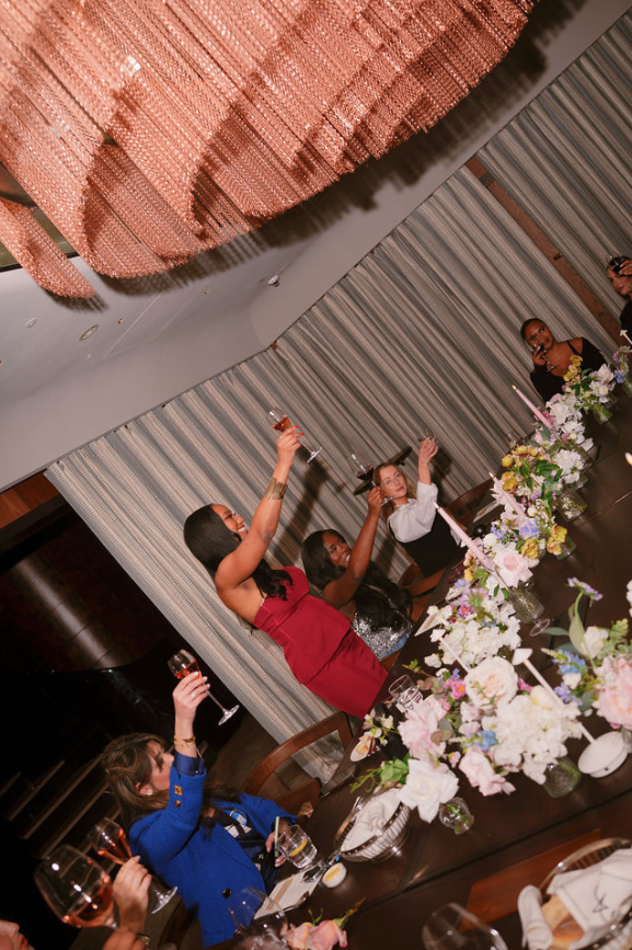 Women raising a toast around a flower-filled dinner table